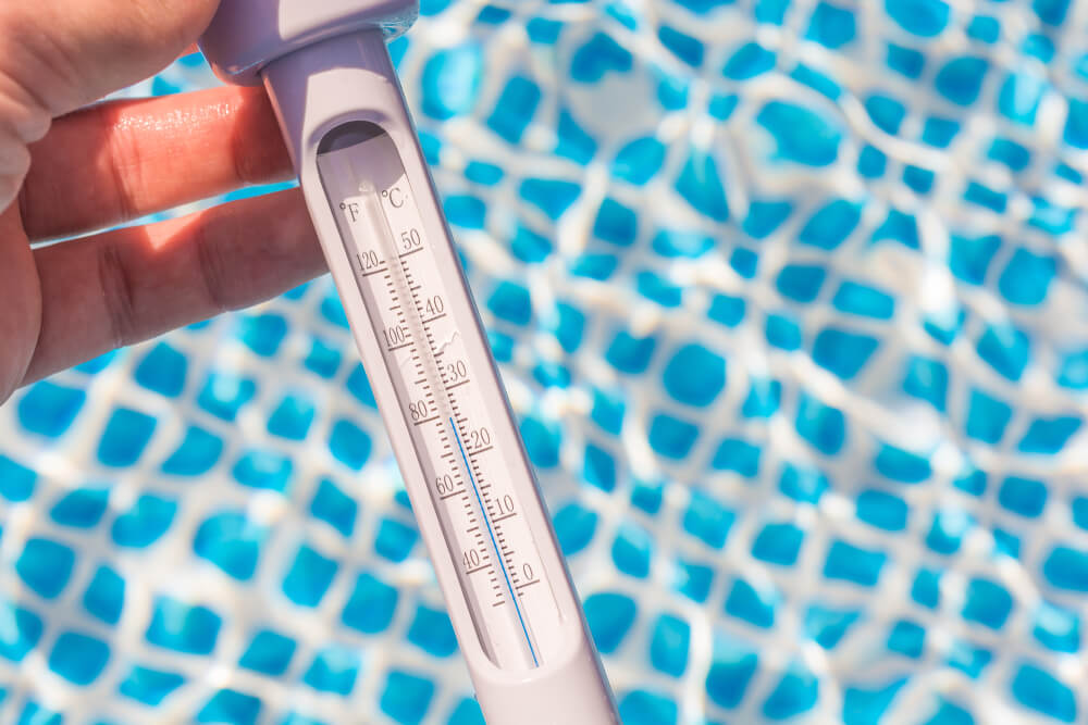 Measuring the Water Temperature in the Pool With a Thermometer