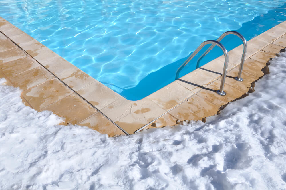 Blue Water of a Swimming Pool With Outdoor Terrace Covered in Snow