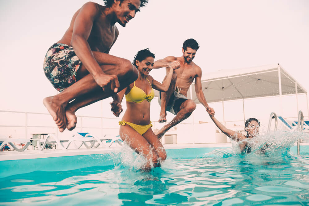 Group of Beautiful Young People Looking Happy While Jumping Into the Swimming Pool Together
