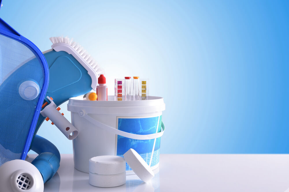 Chemical Cleaning Products and Tools for Pool Water on White Table and Blue Mosaic Background.